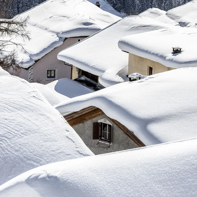 Besneeuwde daken van oude huizen, van dichtbij.